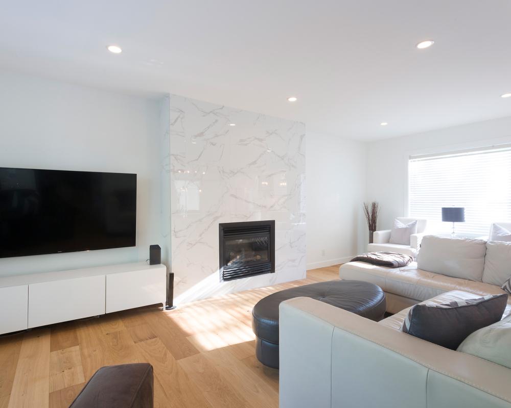 Contemporary living space featuring large windows, minimalist cabinetry, and marble fireplace surround