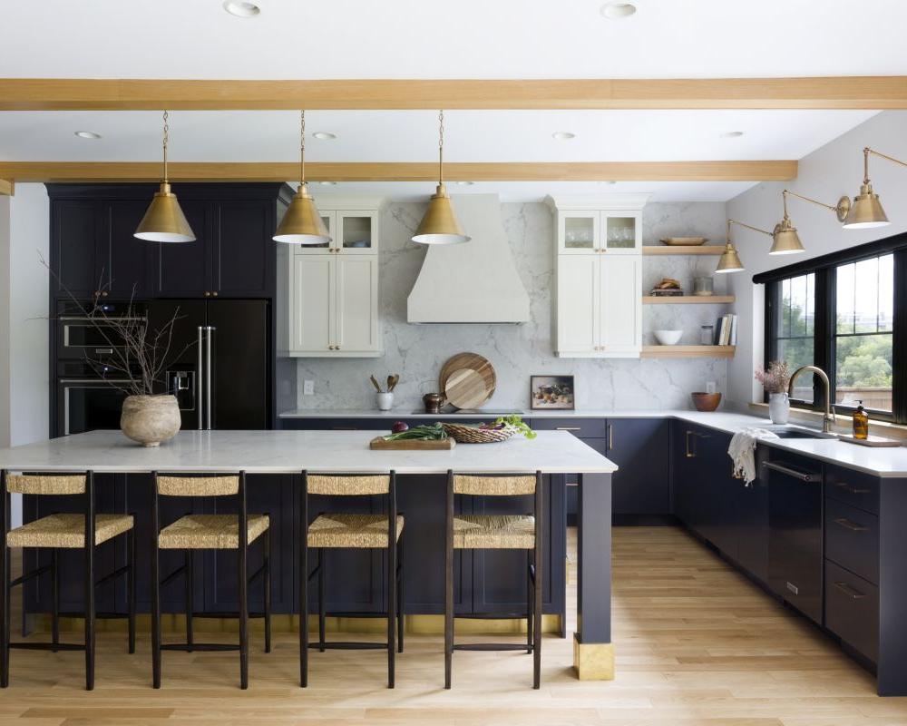 Contemporary kitchen with blue cabinets, marble backsplash, gold lighting, large island, and black-framed windows