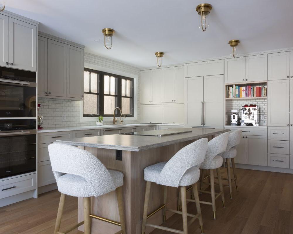 Modern kitchen with large island, custom millwork and cabinets, built-in appliances, and upholstered bar stools