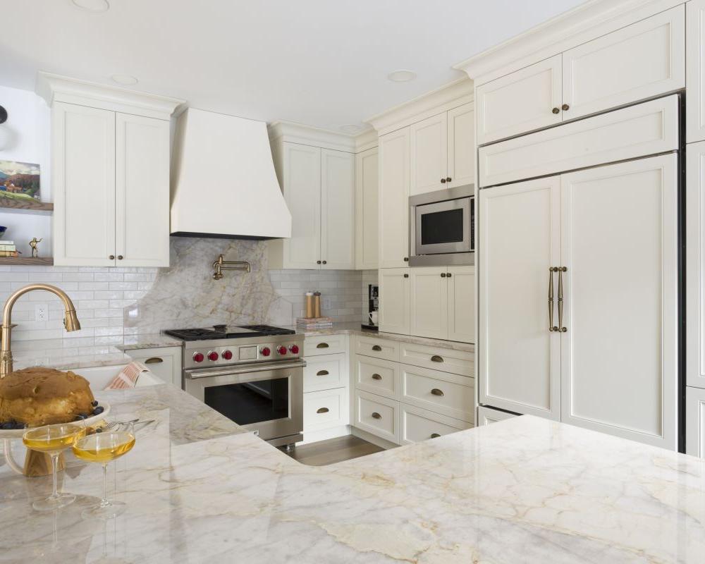 Custom luxury kitchen with high end countertops, gold accessories, hidden range, and paneled refrigerator