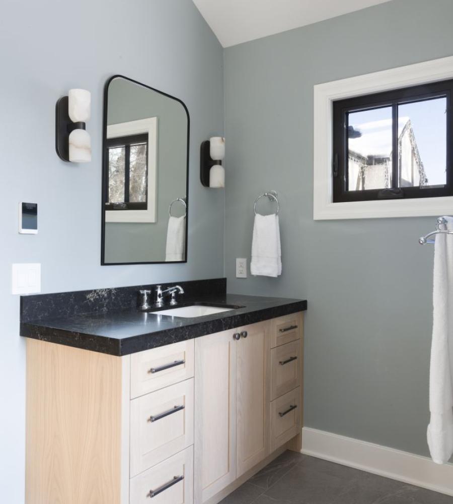 Bathroom vanity with dark countertops and accent wood stain